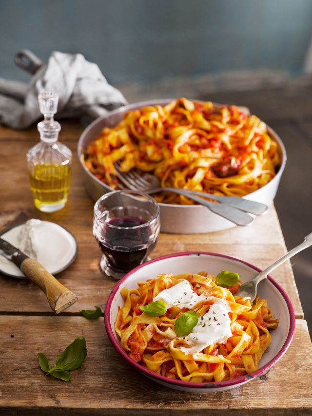 a bowl of pasta with sauce and a fork on a table