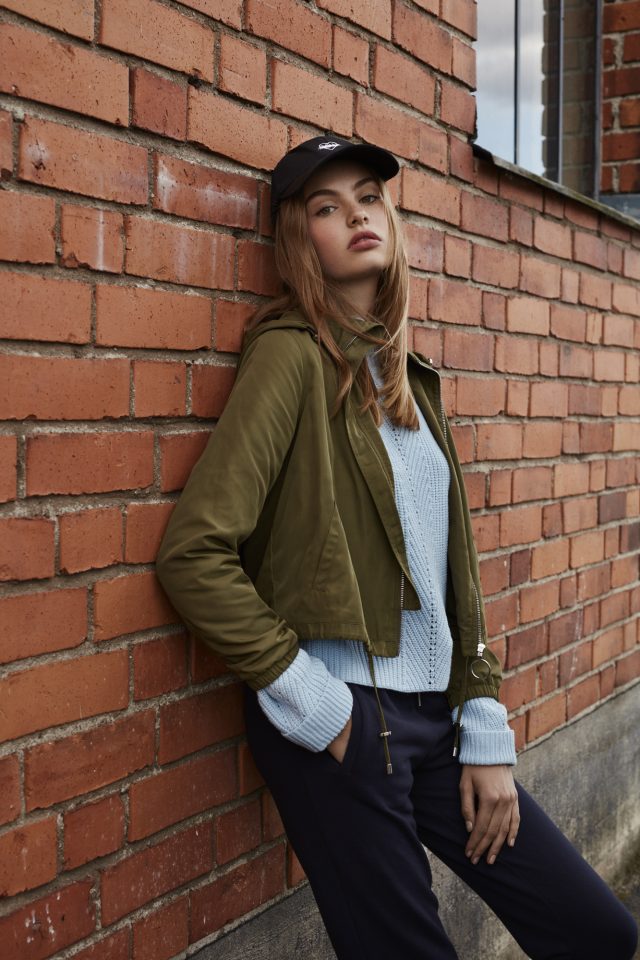 a woman leaning against a brick wall
