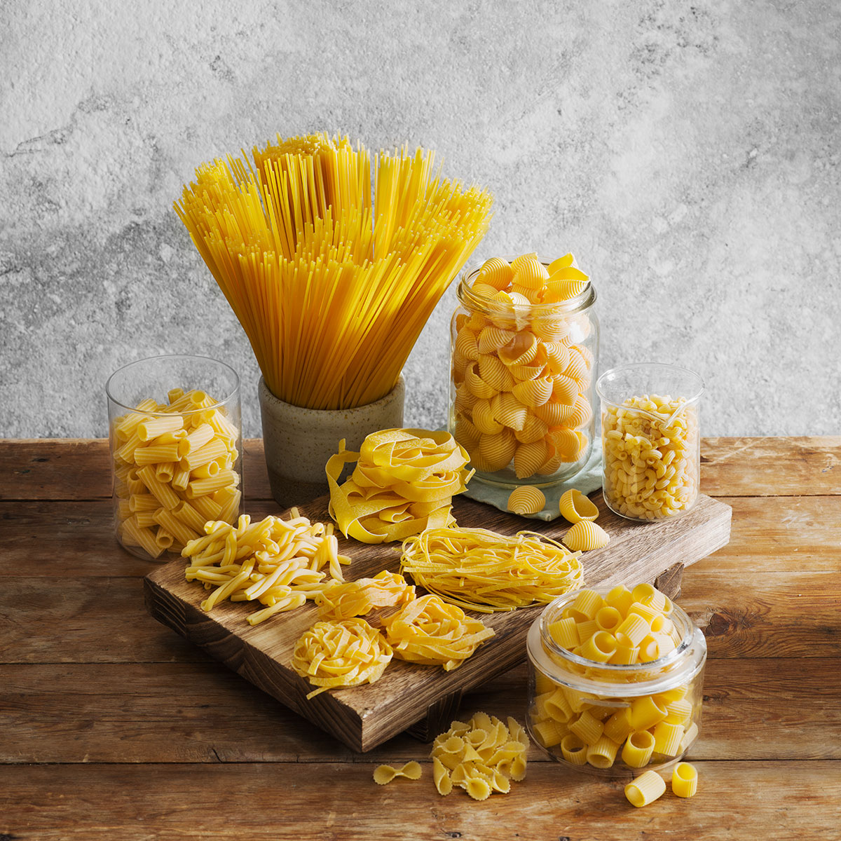 a variety of pasta on a wooden board