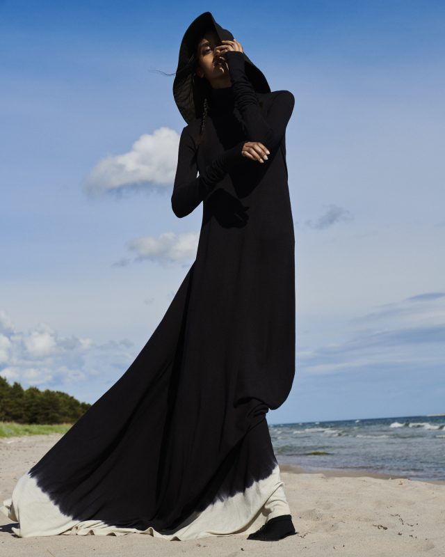 a woman in a black dress on a beach