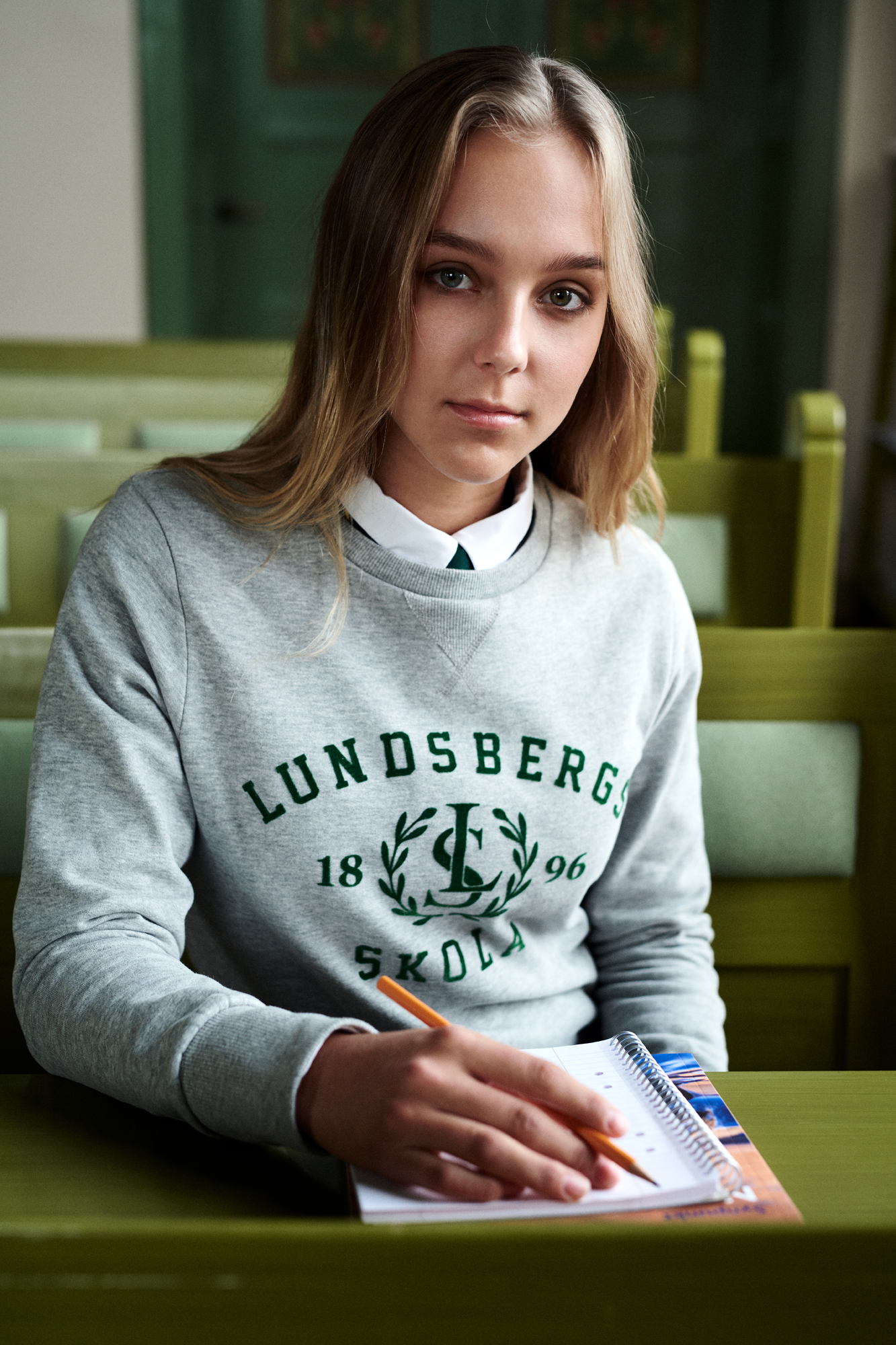a woman sitting at a table holding a pencil and notebook