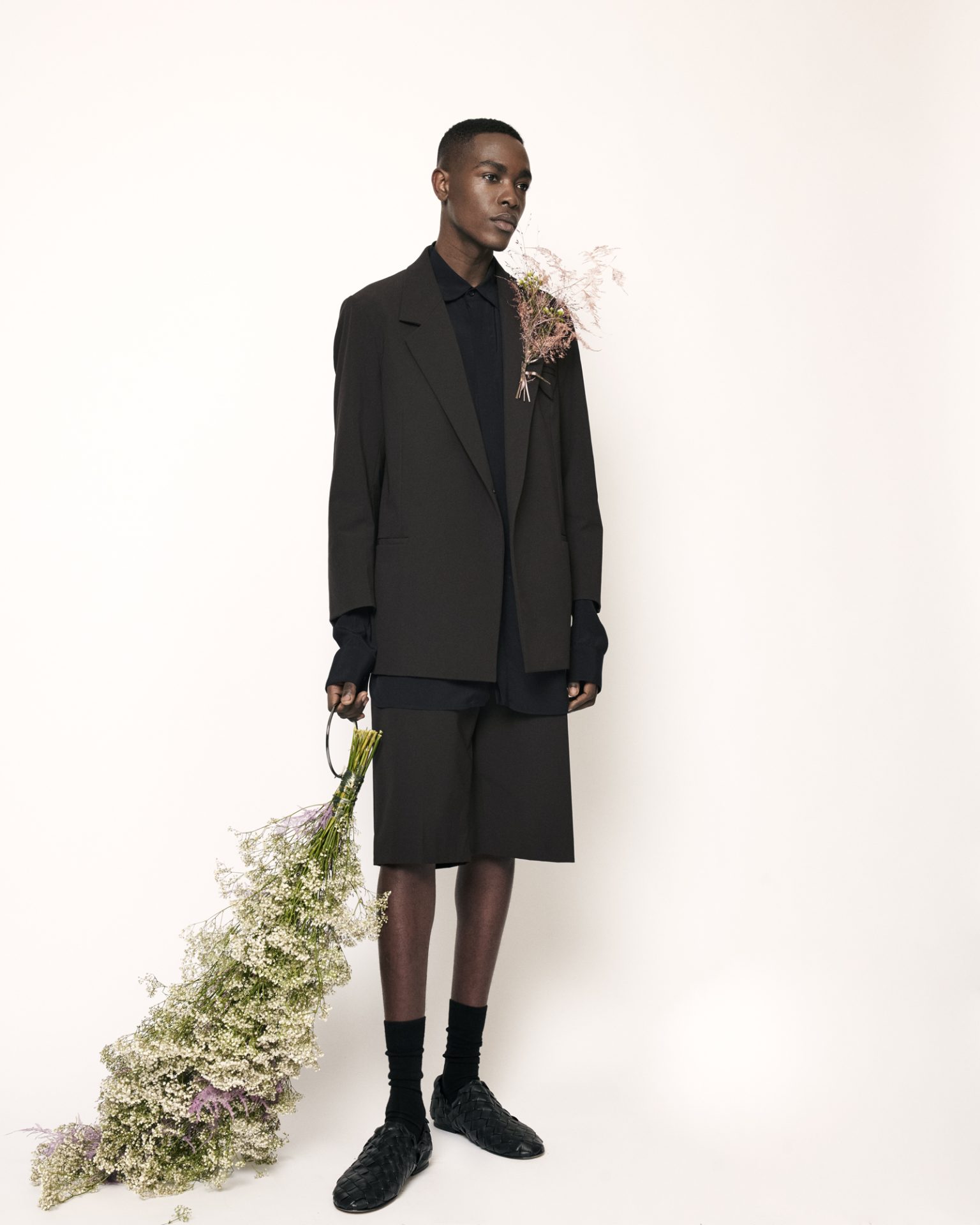 a man in a black suit holding a bouquet of flowers