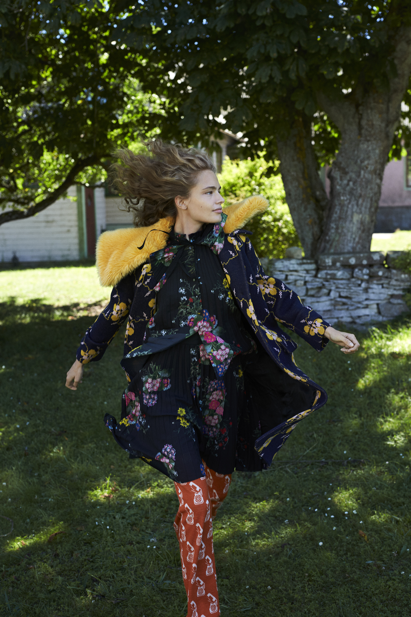 a woman in a floral dress and a yellow fur collar running