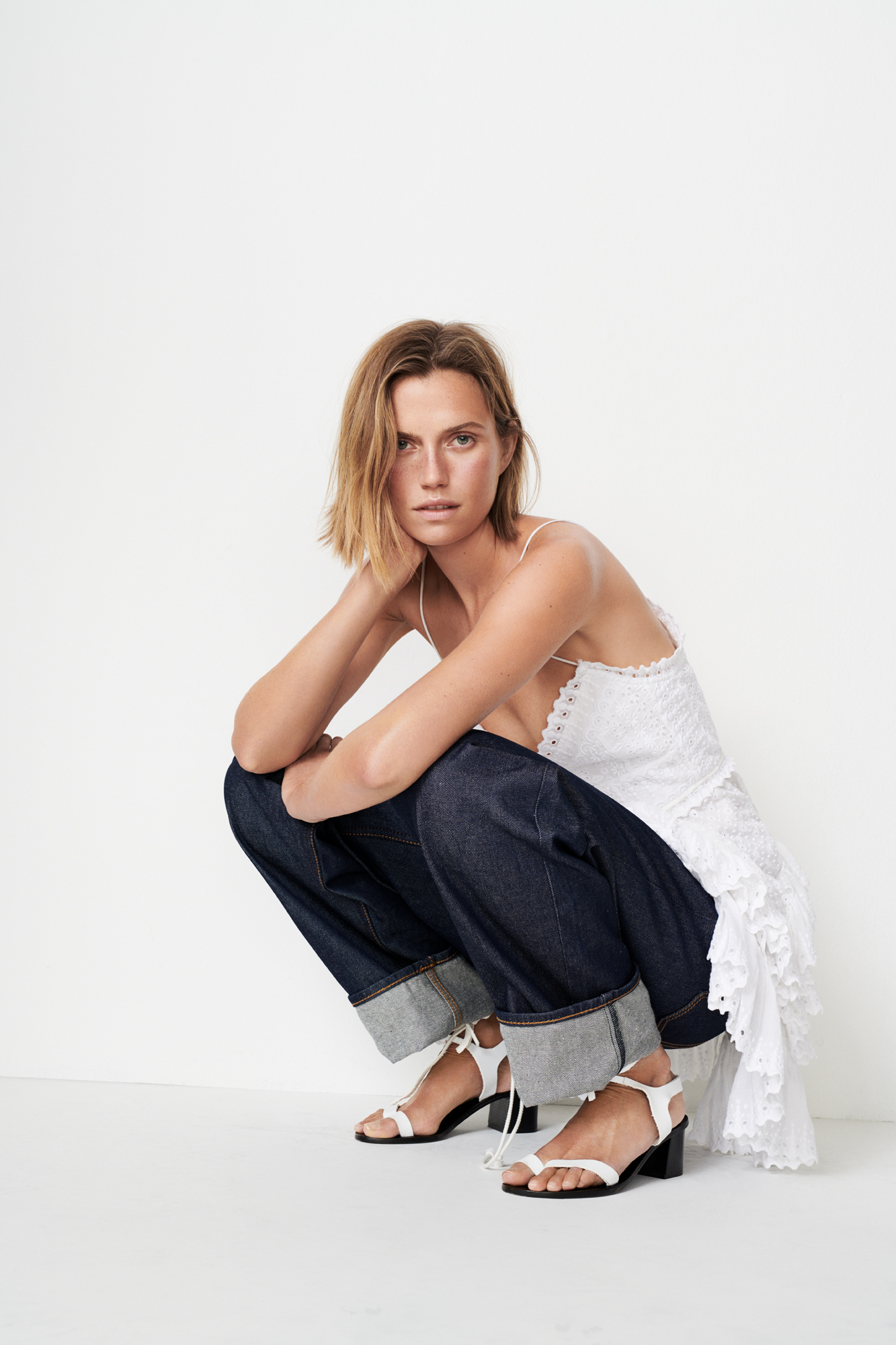 a woman in white dress and jeans squatting