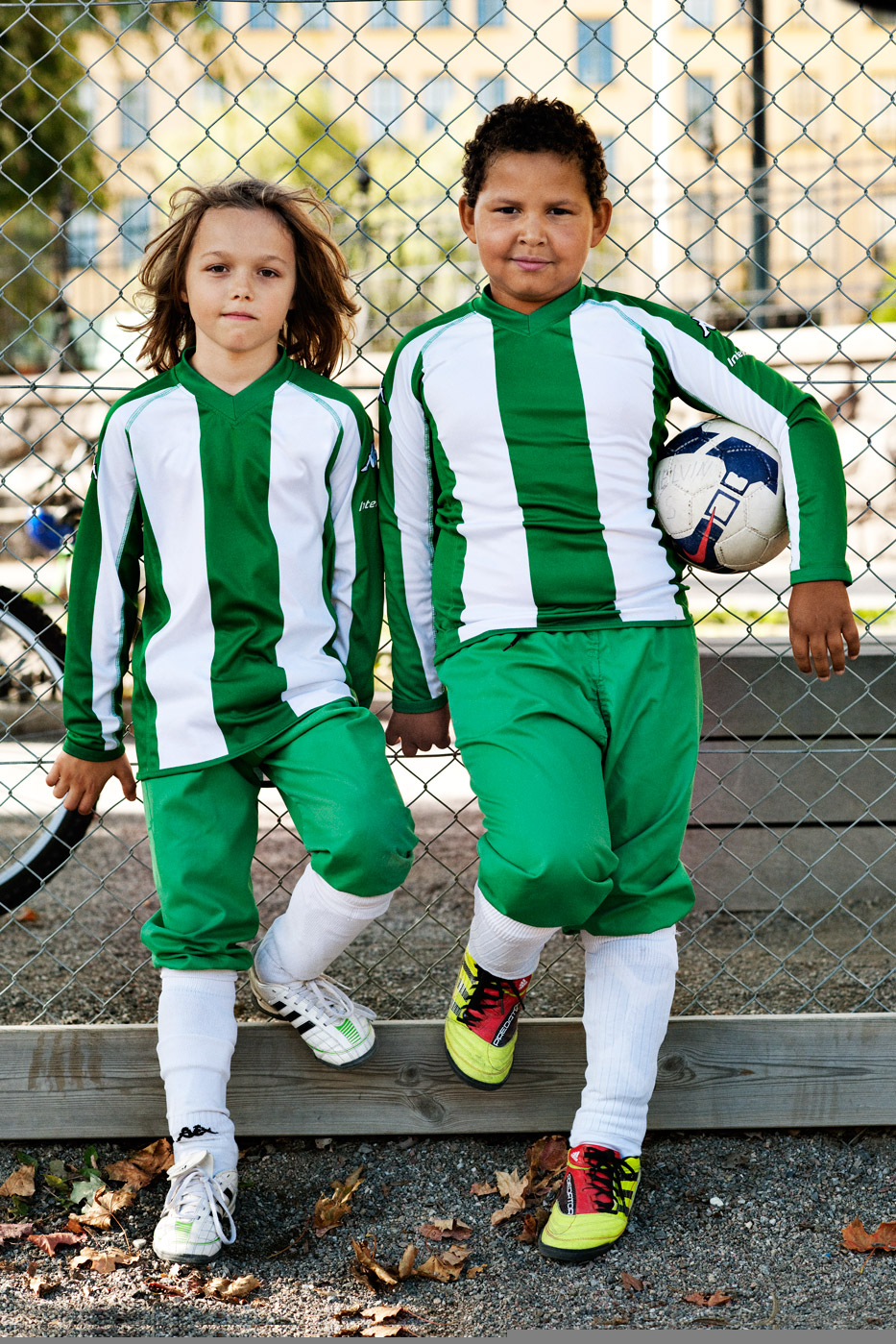 a couple of young boys in green and white sports uniforms