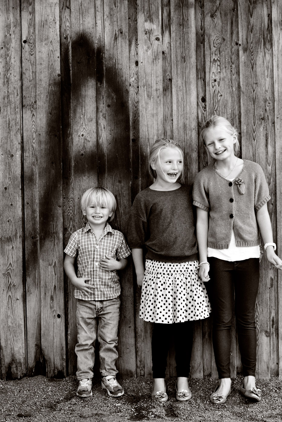 a group of children standing in front of a wooden wall
