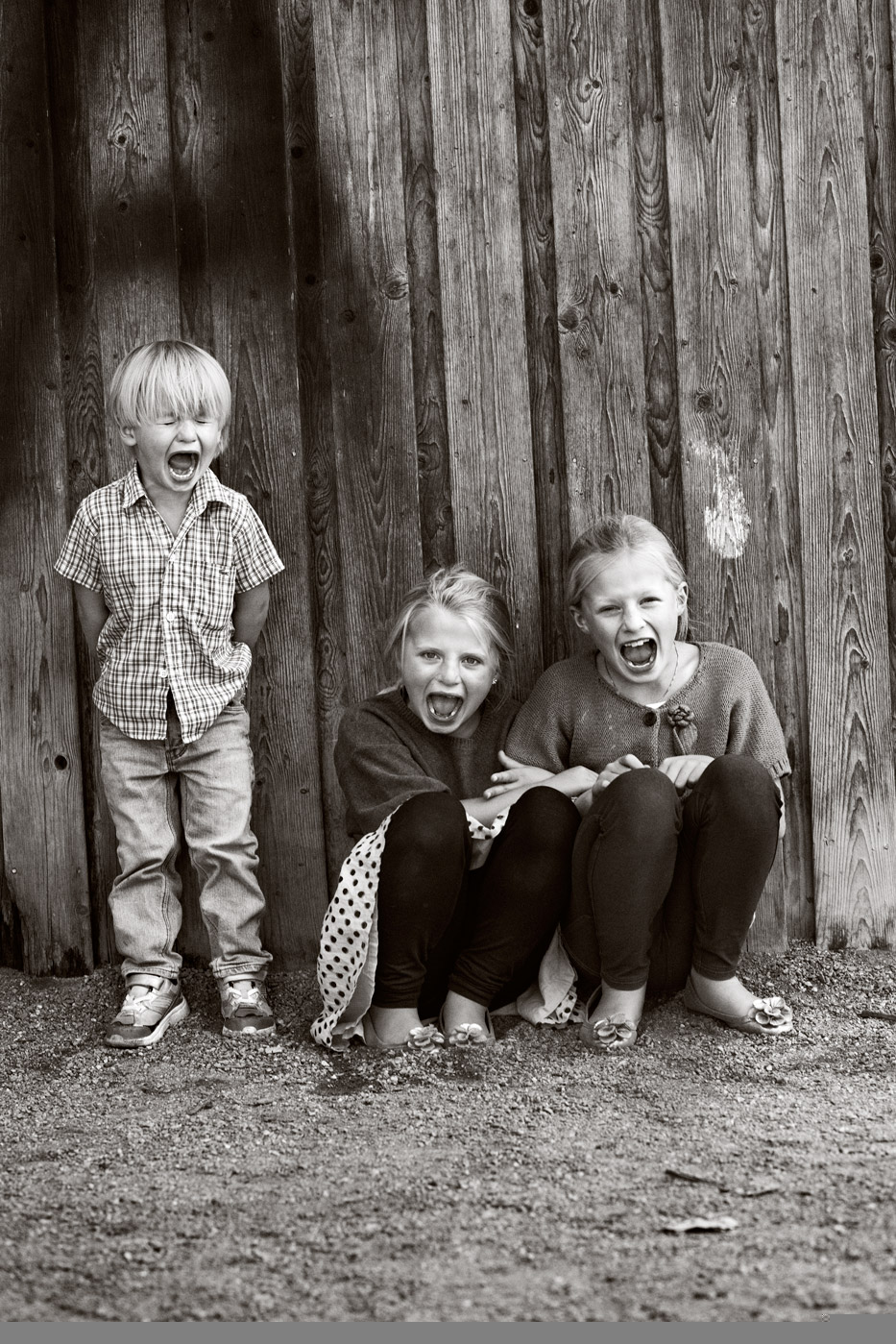 a group of children sitting in front of a wooden wall