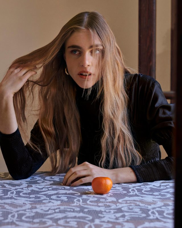 a woman sitting at a table with a fruit