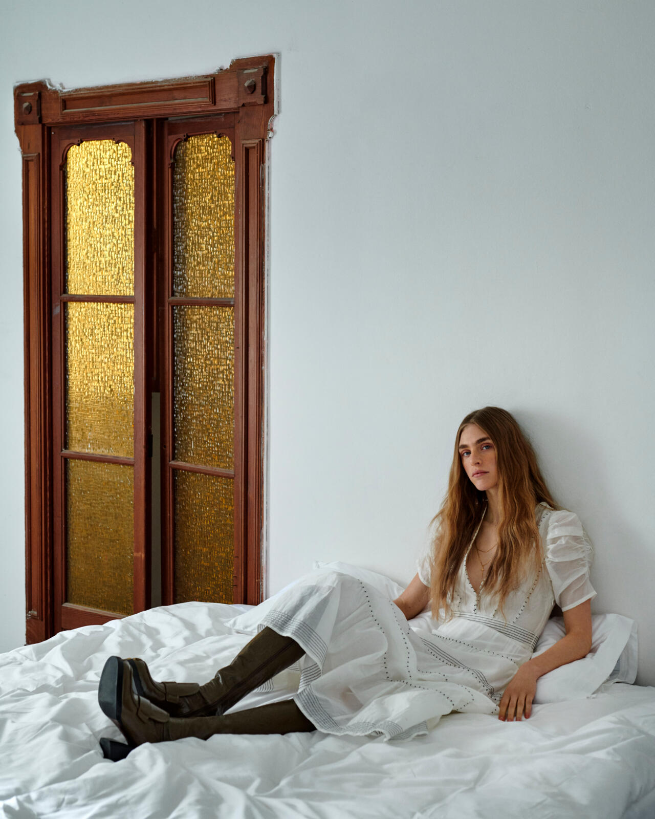 a woman in a white dress sitting on a bed