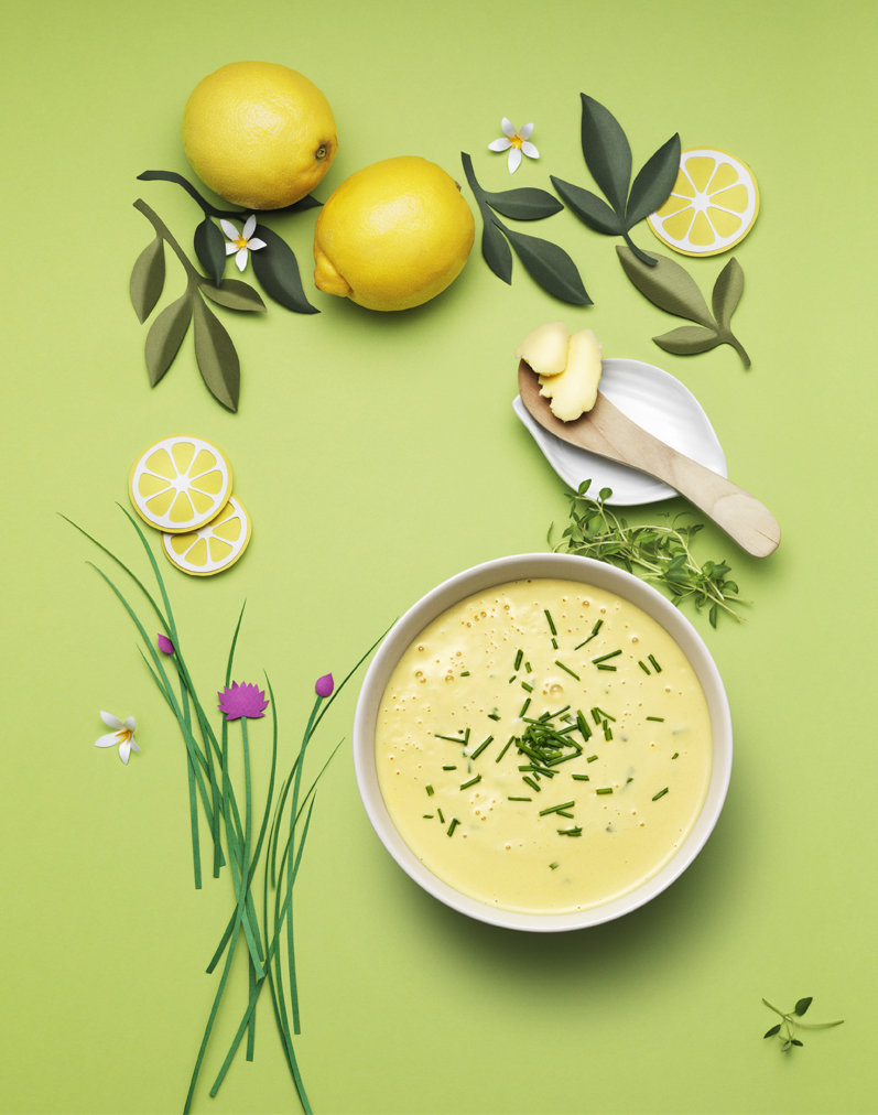 a bowl of soup with herbs and lemons