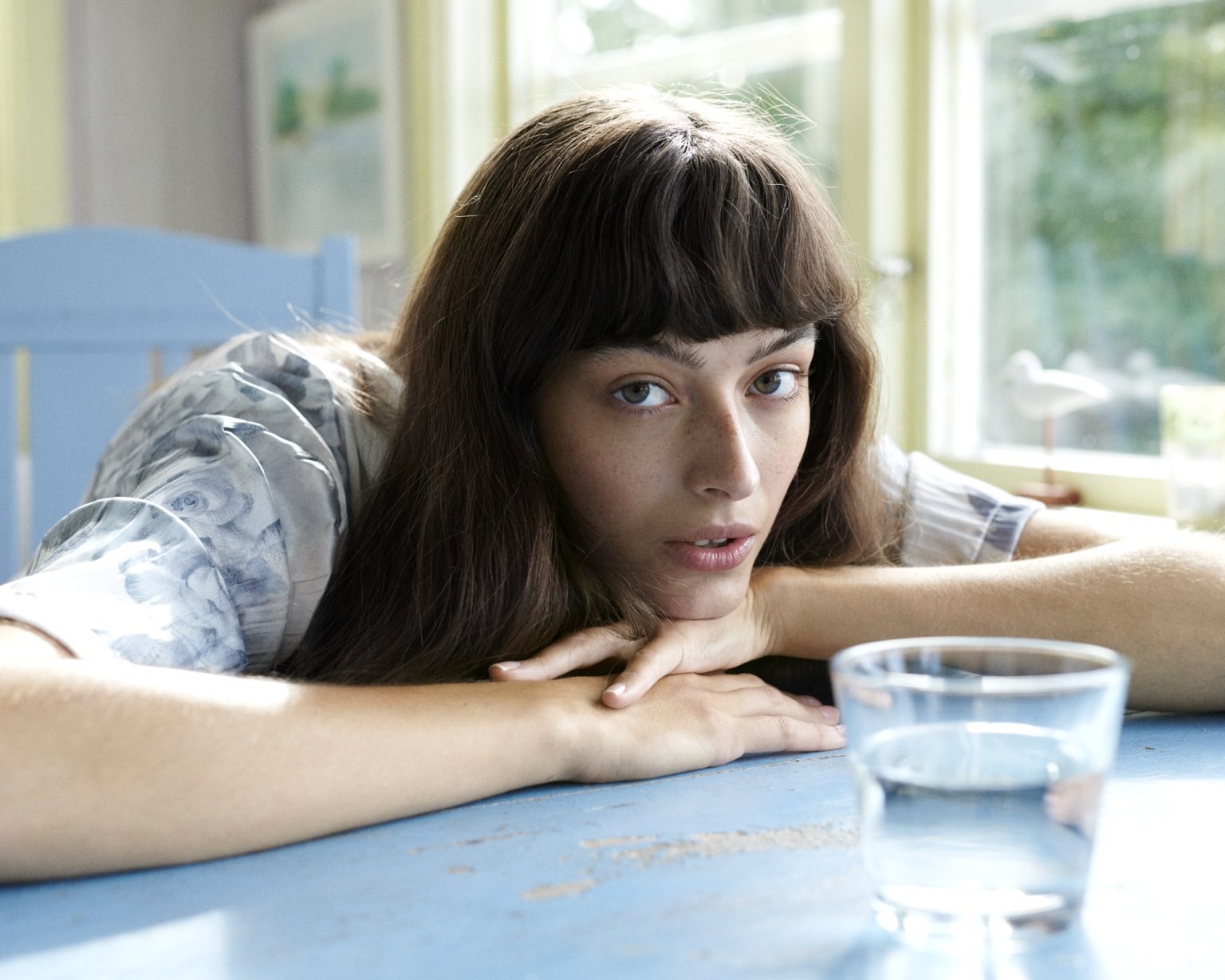 a woman leaning on a table with her arms crossed