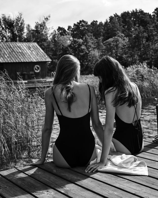 two women sitting on a dock by water