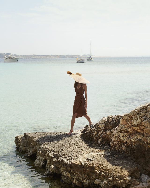 a woman walking on a rock by the water