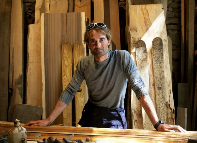 a man standing in front of a woodworking table
