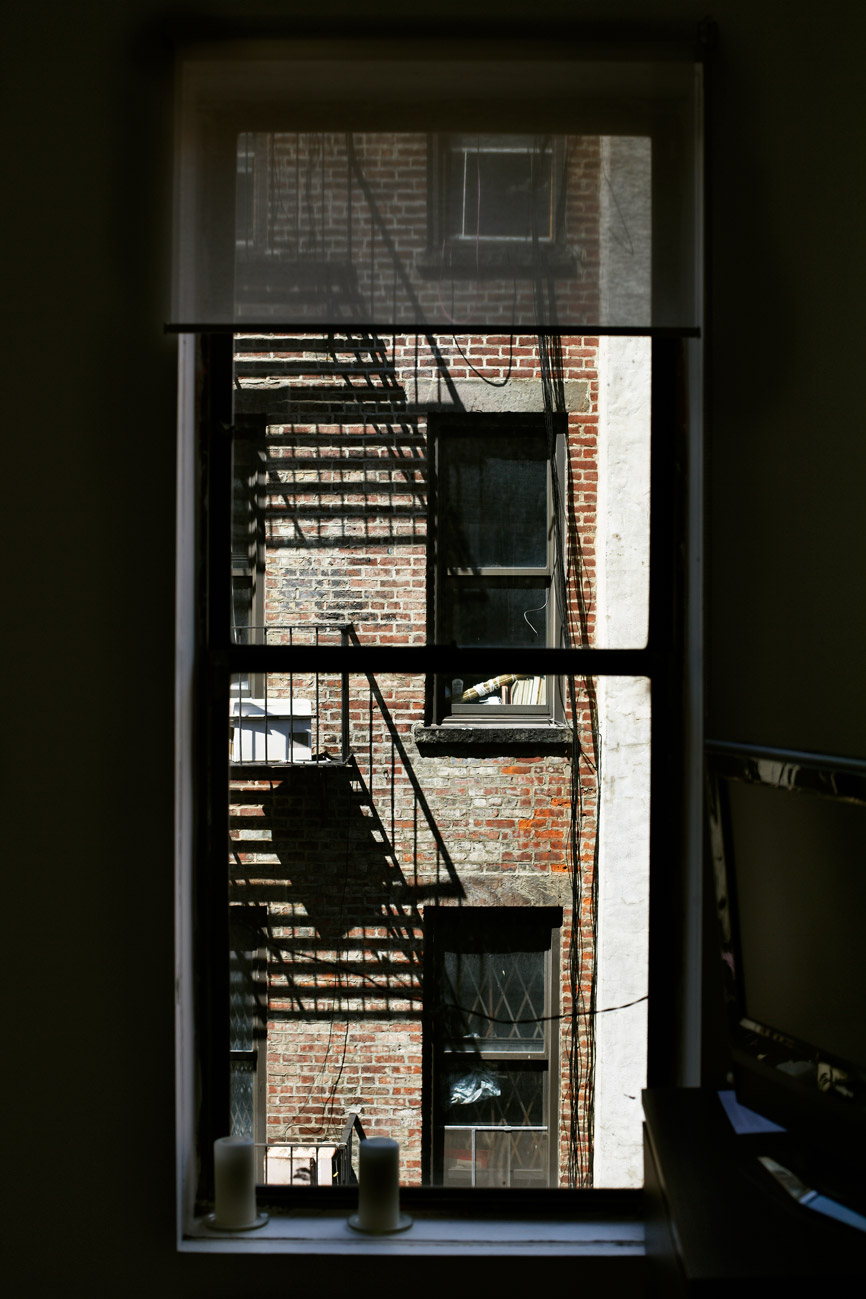 a window with a brick building and fire escape stairs