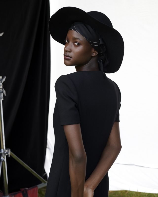 a woman in a black dress and hat