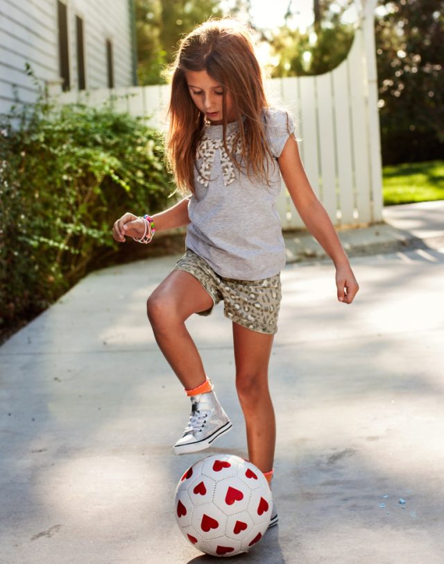 a girl standing on a football ball