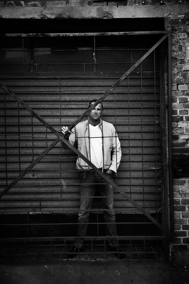 a man standing behind a metal gate
