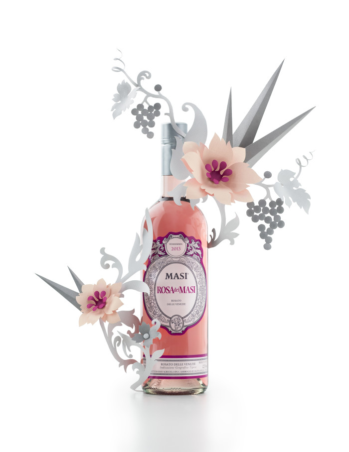 a bottle of pink liquid with paper flowers and leaves