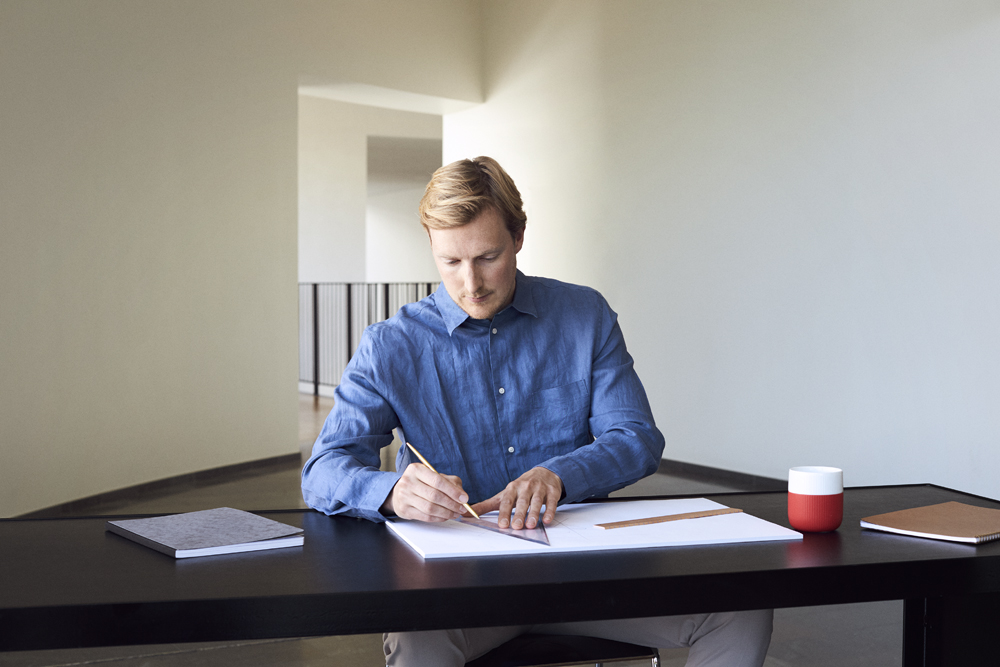 a man sitting at a table drawing on a piece of paper