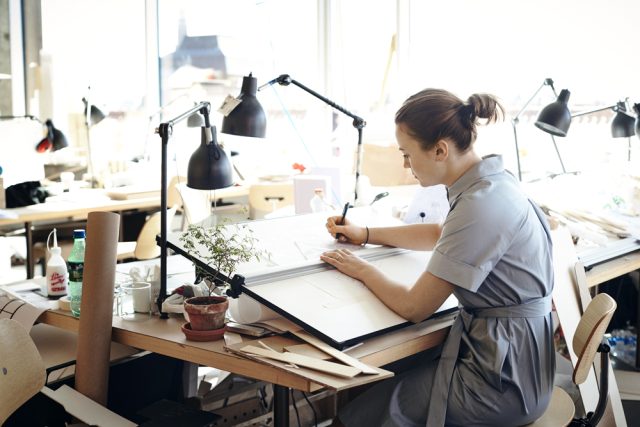 a woman sitting at a desk writing on a paper