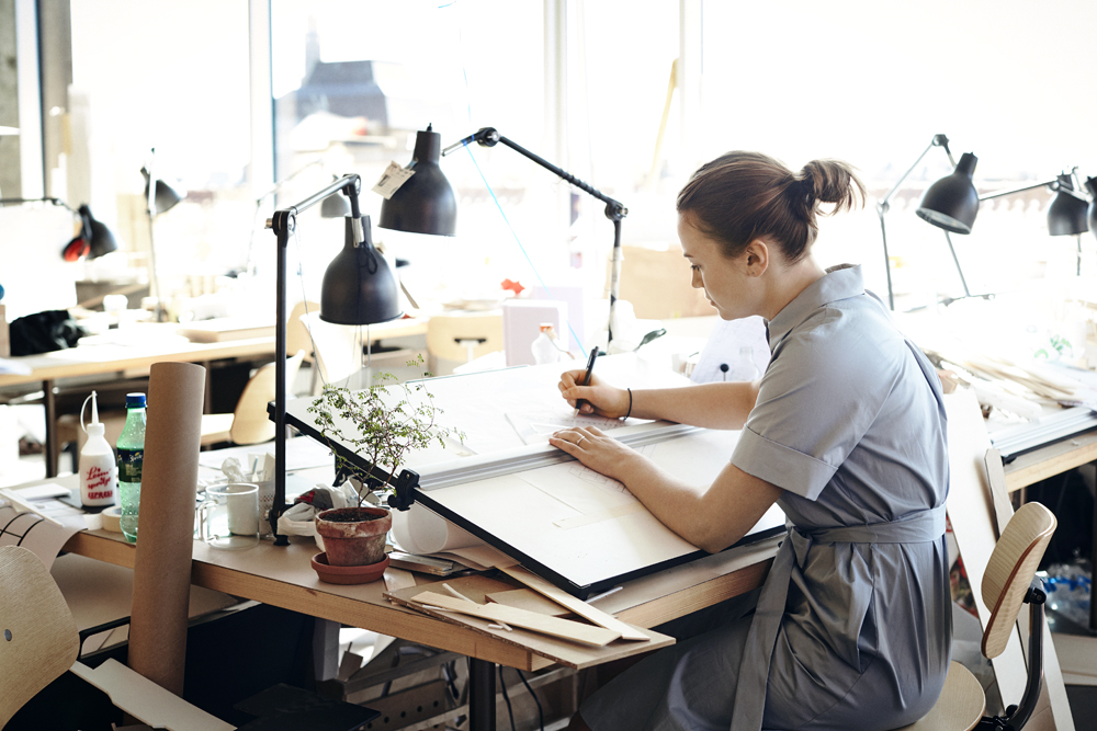 a woman sitting at a desk writing on a paper