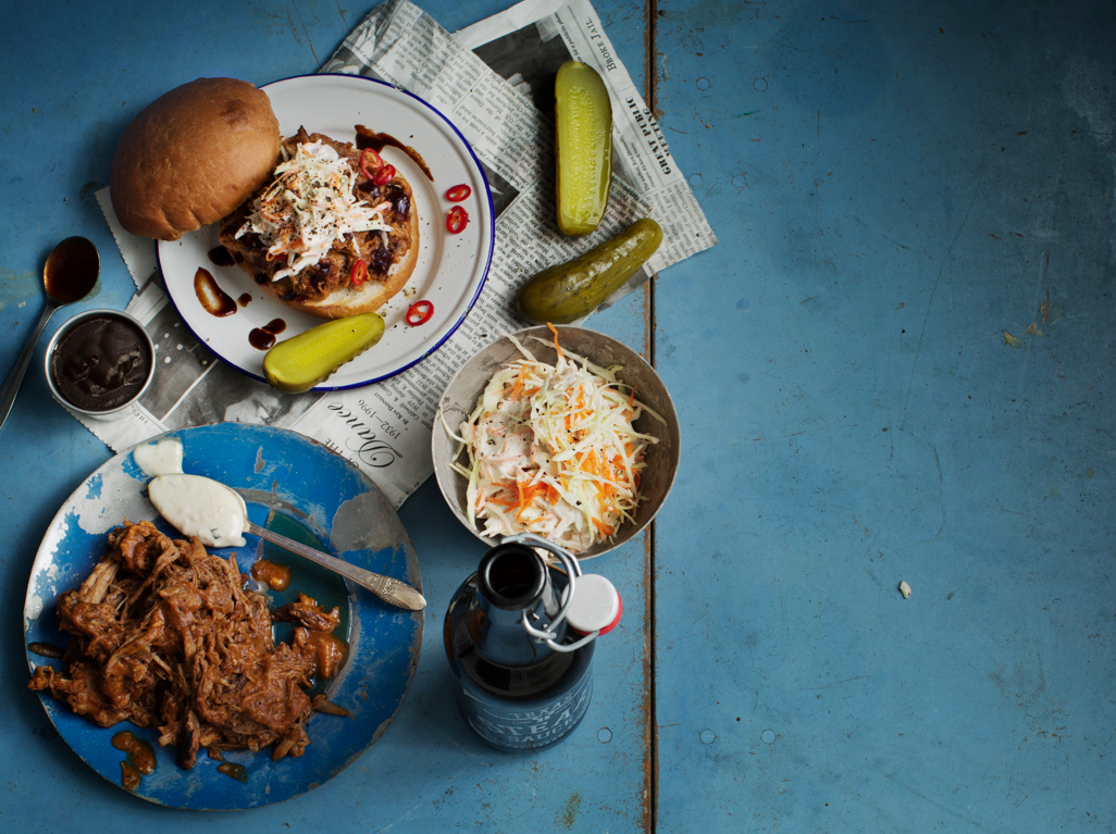 a plate of food and a bottle of beer on a blue table