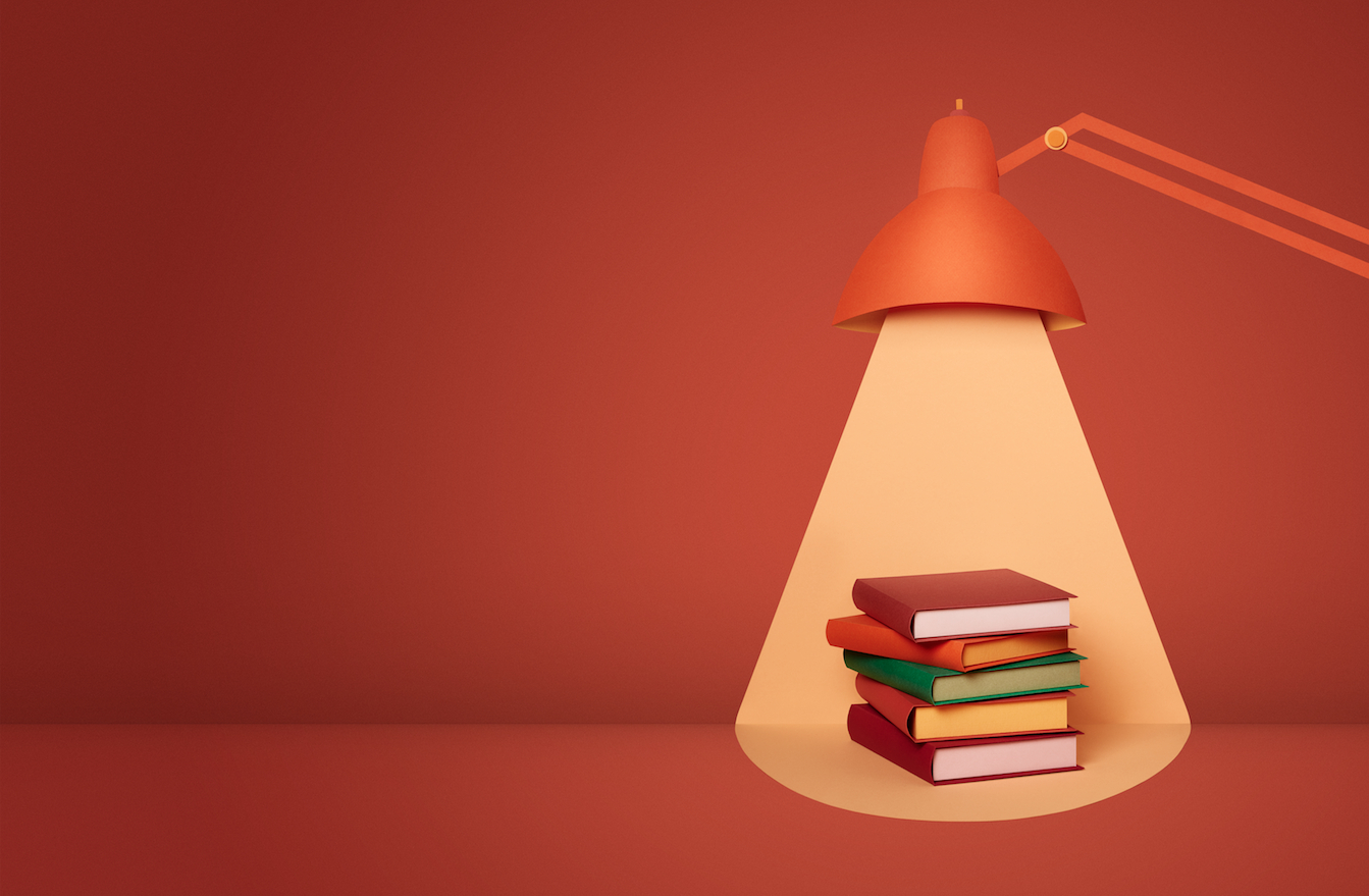 a stack of books under a lamp