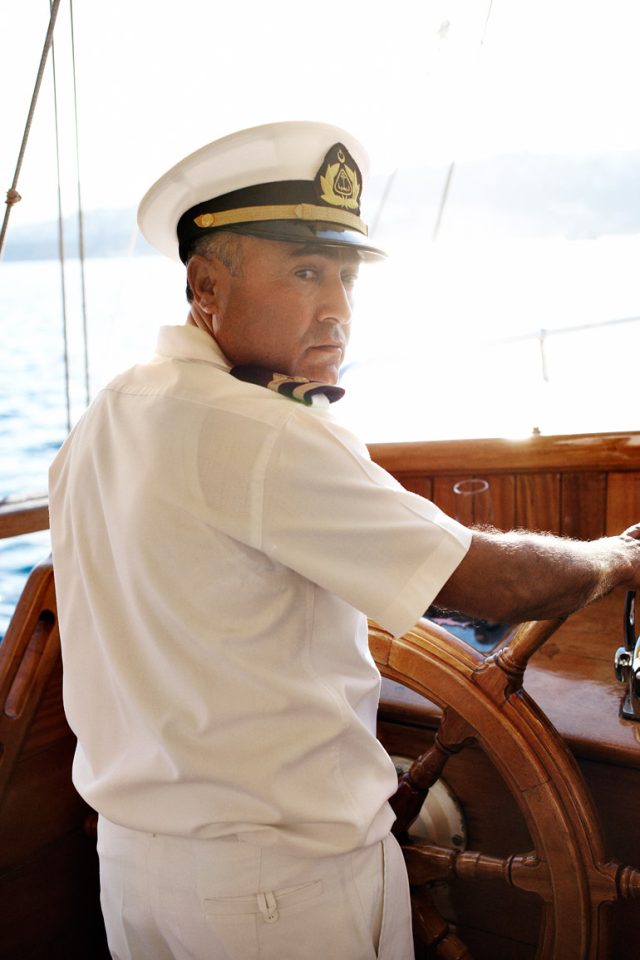 a man in a white shirt and white shirt driving a boat