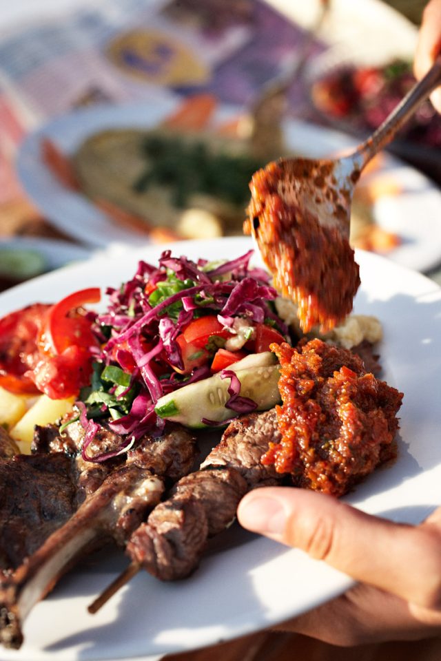 a hand holding a spoon over a plate of food