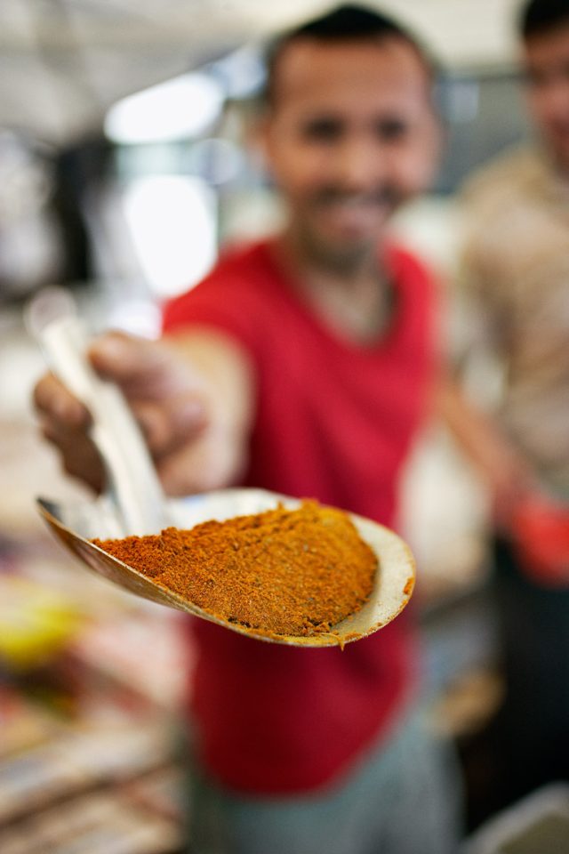 a man holding a spoon full of spices
