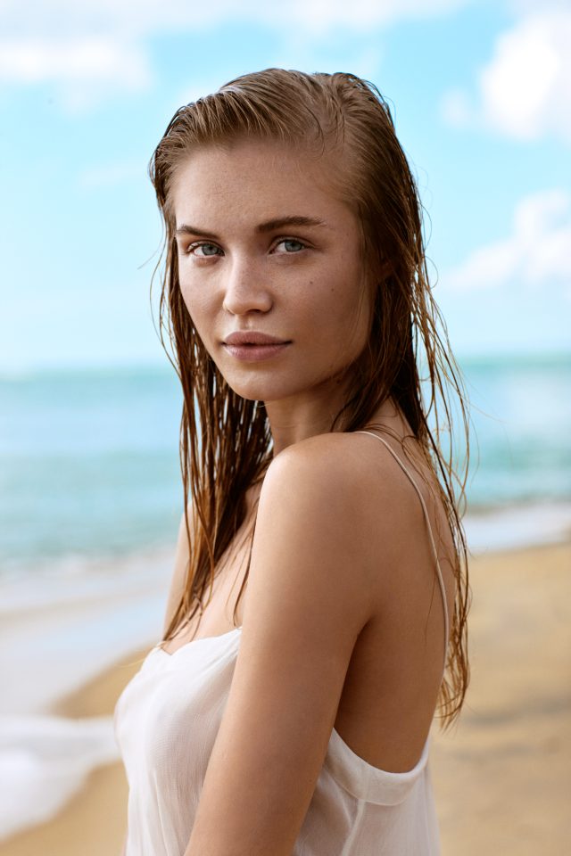 a woman with wet hair standing on a beach