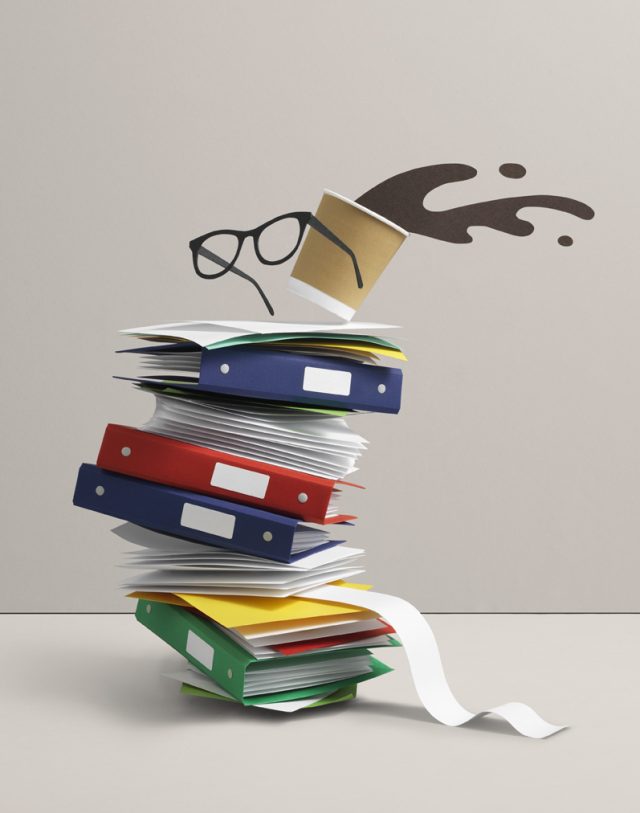 a stack of files with a paper cup and glasses on top