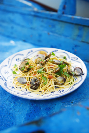 a plate of pasta with clams and parsley