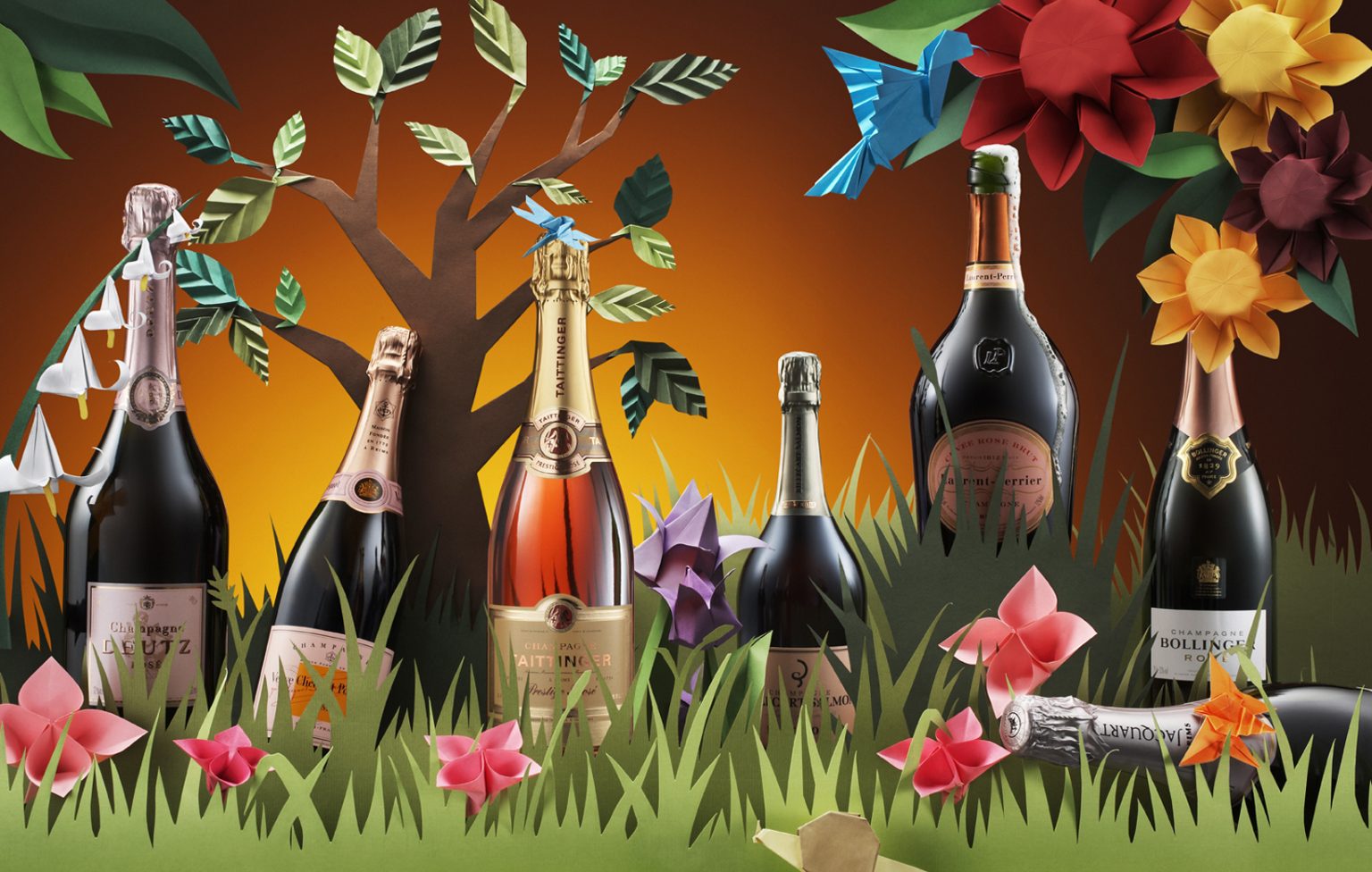 a group of bottles of wine in grass with paper flowers and leaves