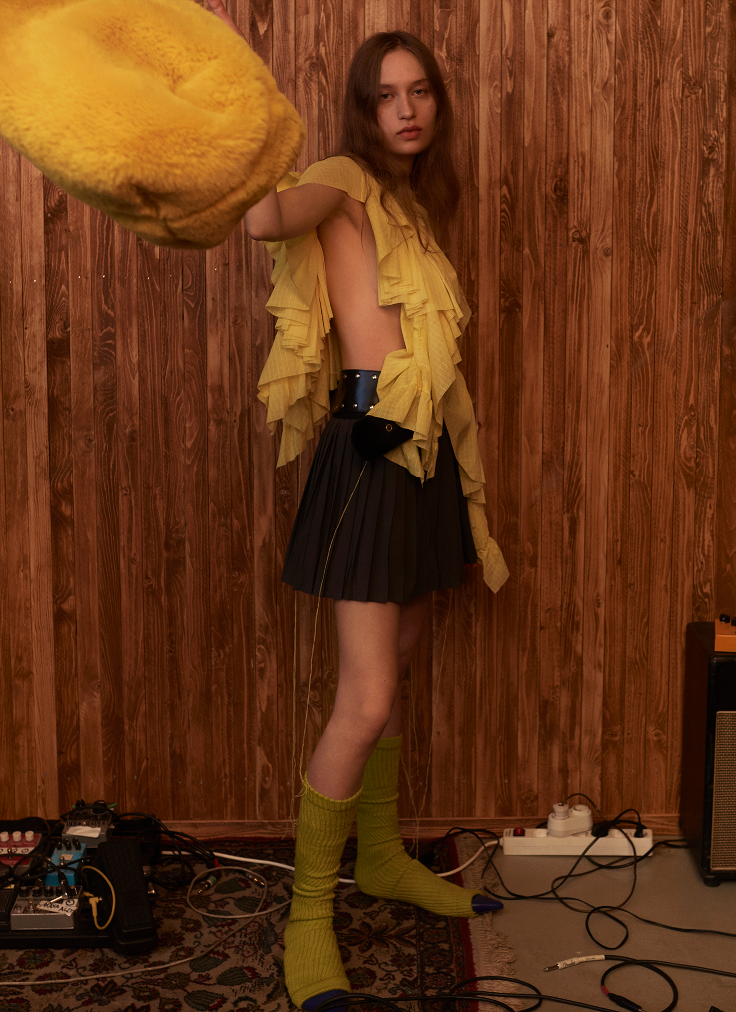 a woman in a skirt and yellow shirt holding a yellow pillow