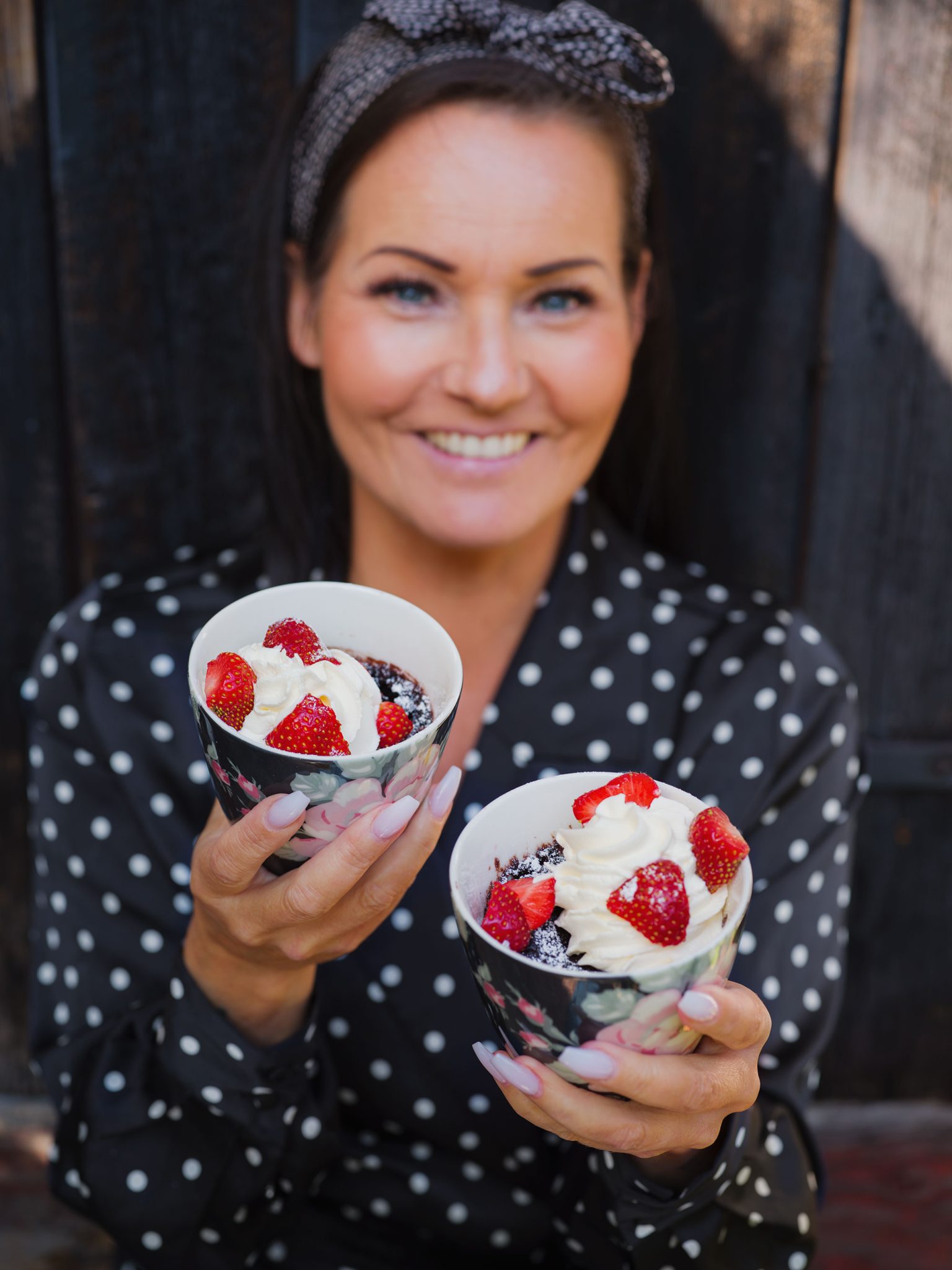 a woman holding two cups of dessert