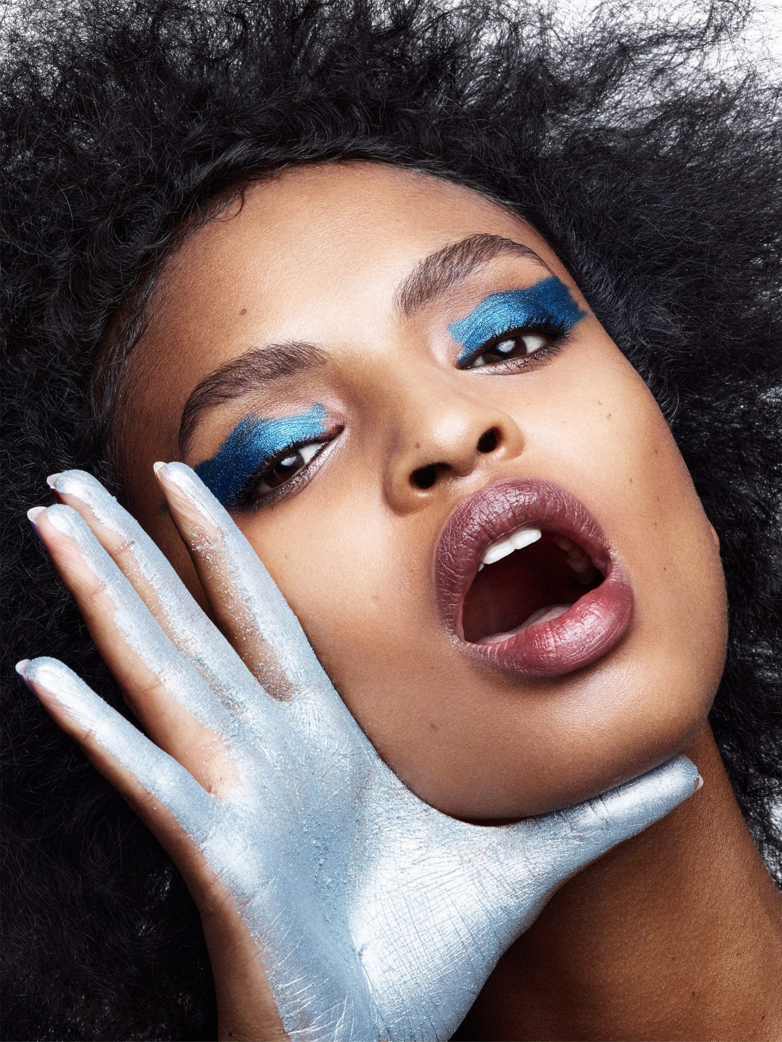a woman with blue makeup and silver hand