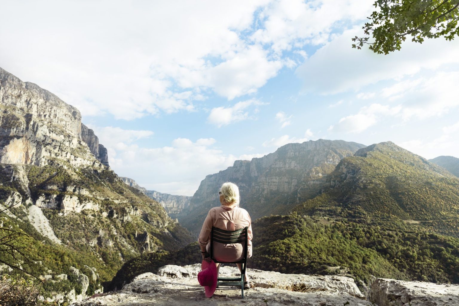 a woman sitting on a chair overlooking a valley