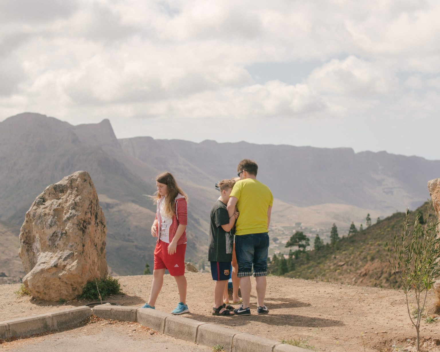 a group of people standing on a road with mountains in the background
