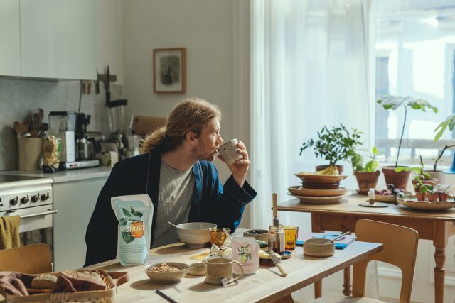 a man sitting at a table drinking from a cup