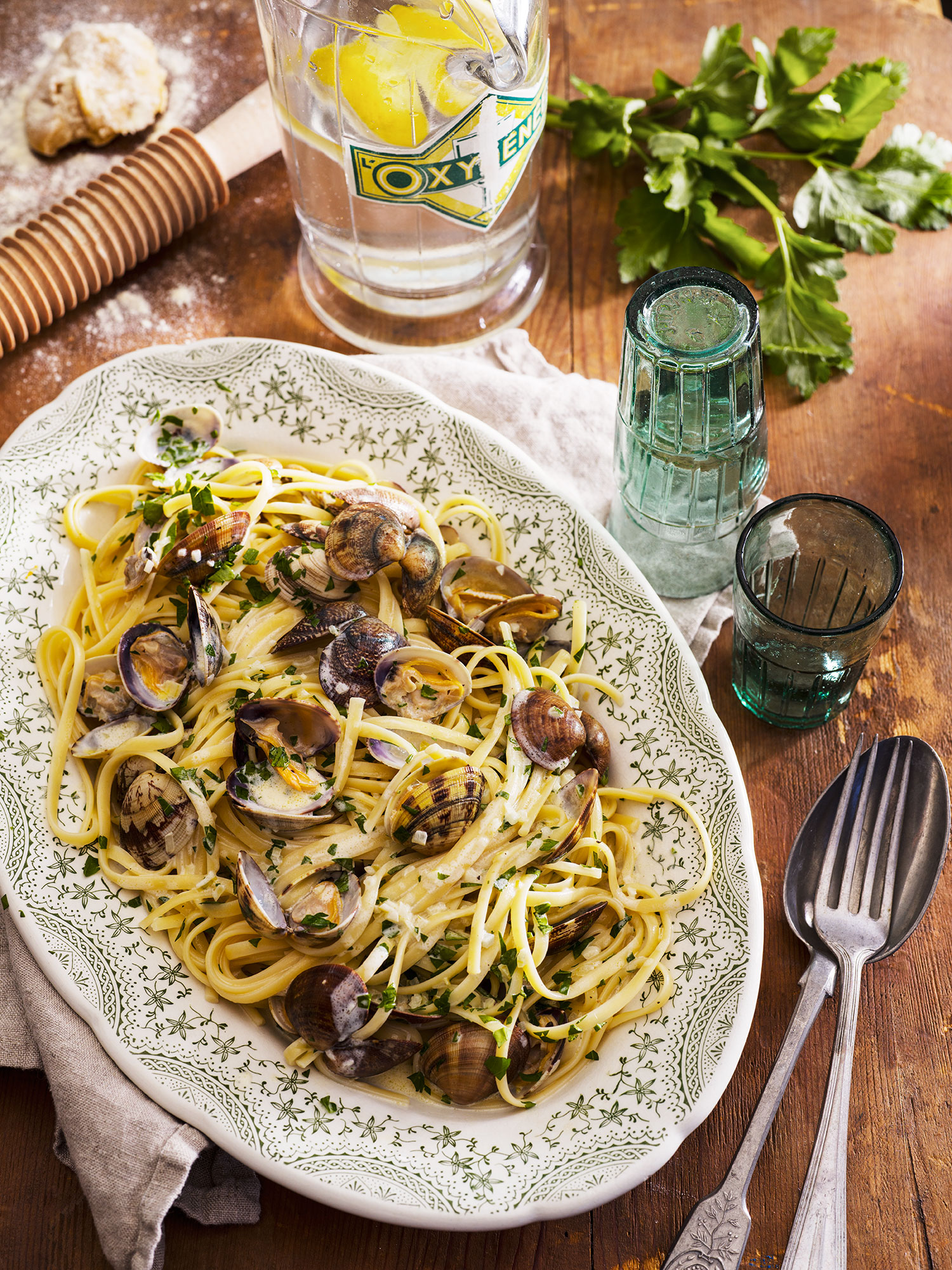 a plate of pasta with clams and a bottle of vodka