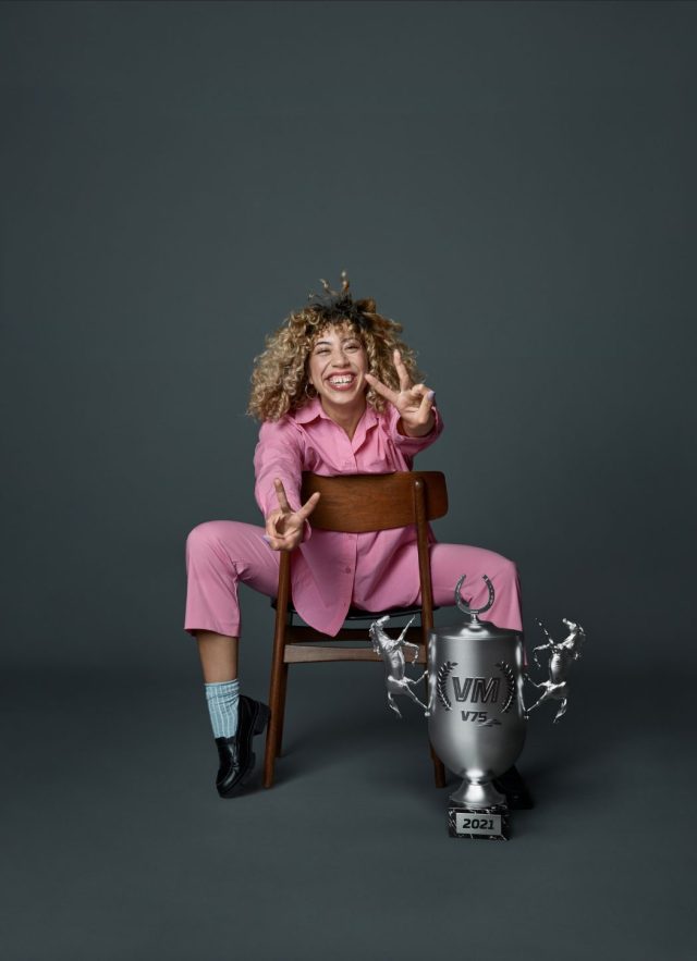 a woman sitting on a chair with a trophy and a peace sign