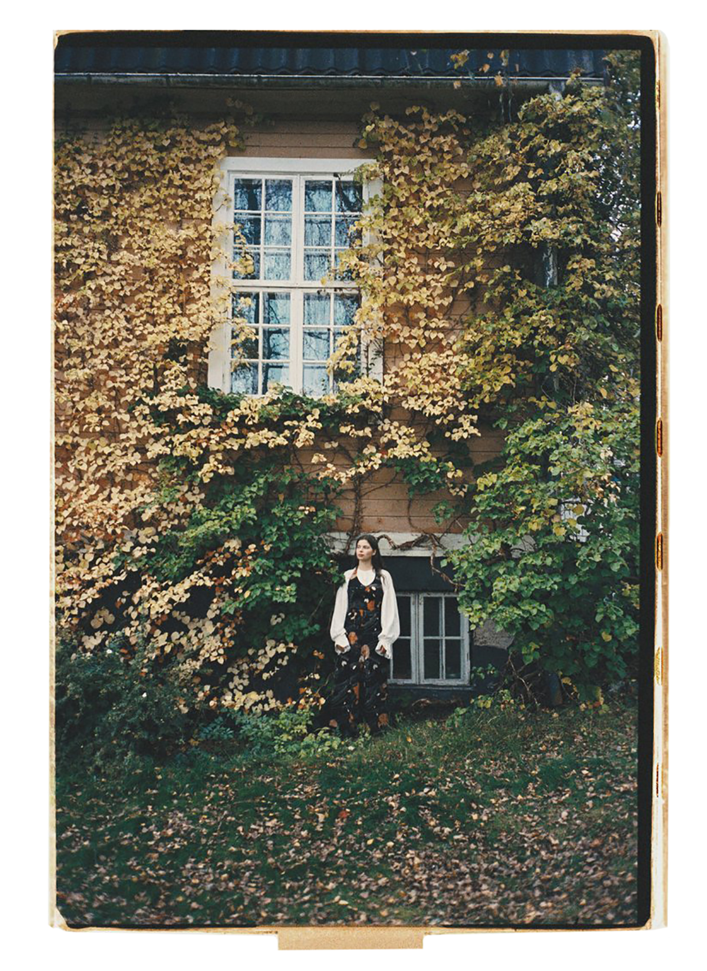 a woman standing in front of a building with ivy on the wall