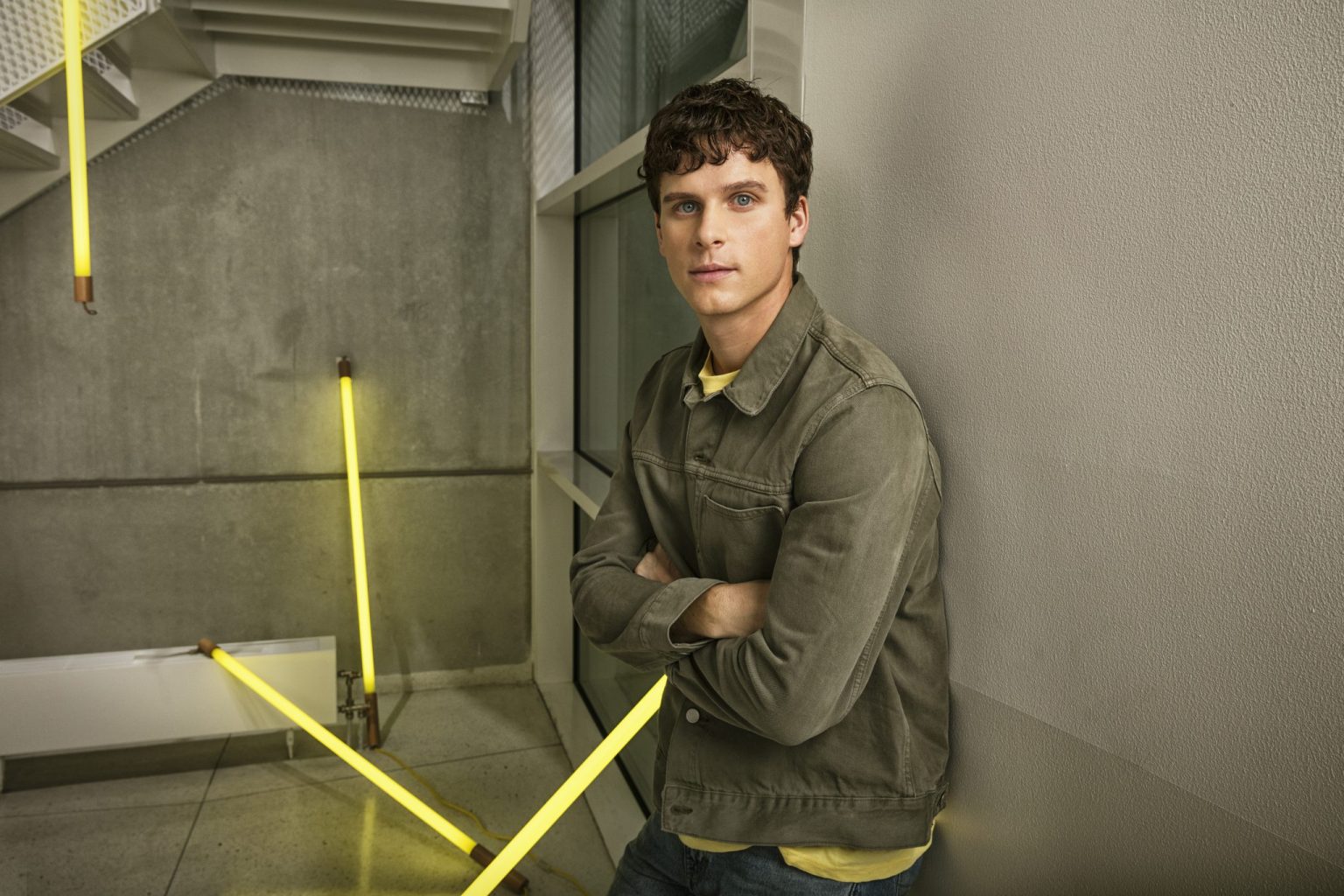 a man leaning against a wall with yellow lights