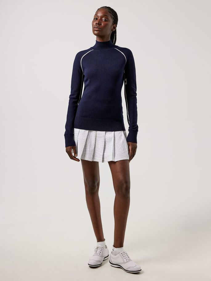 a woman in a blue sweater and white skirt