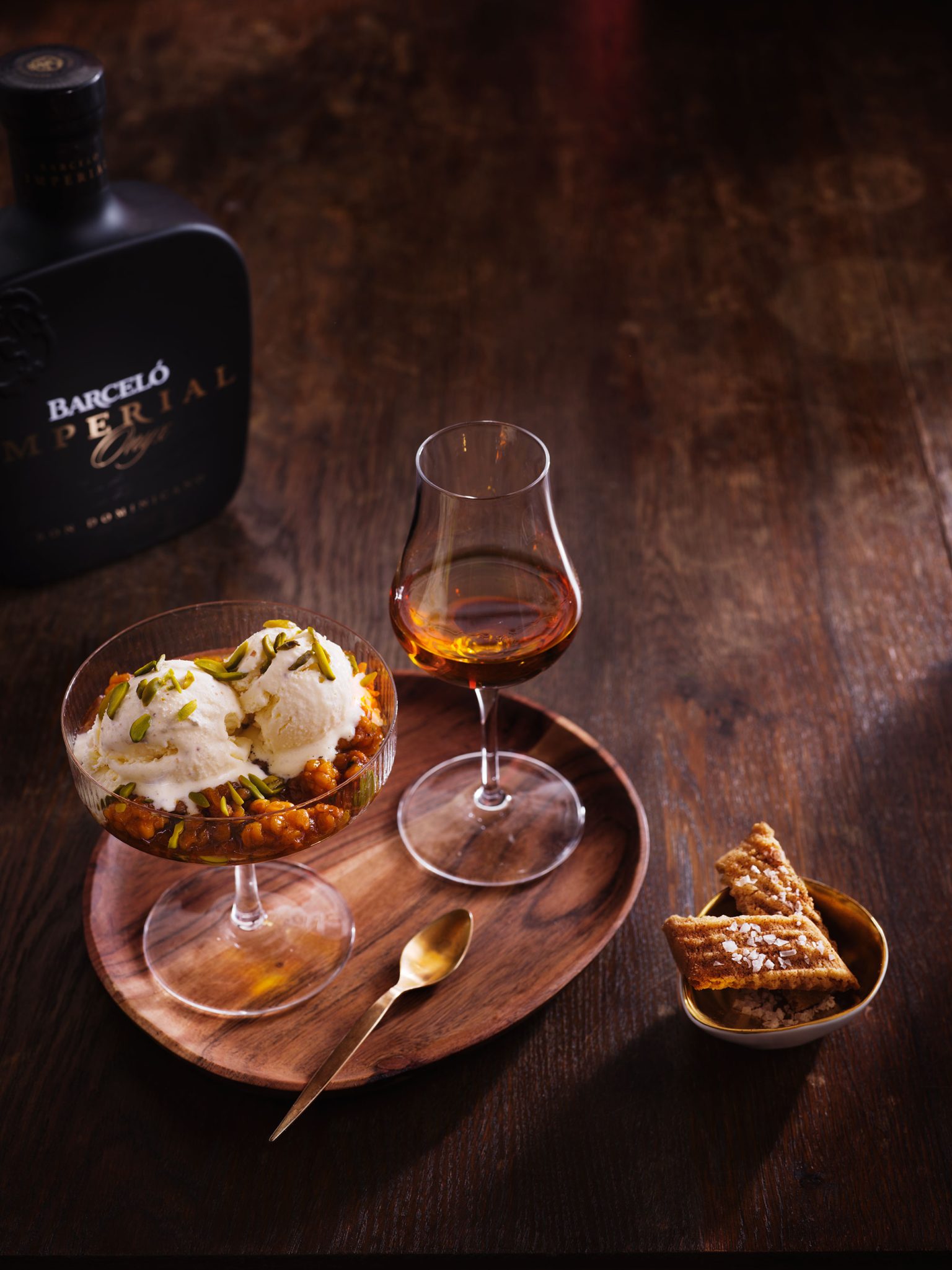 a bowl of ice cream and a glass of liquor on a wooden tray