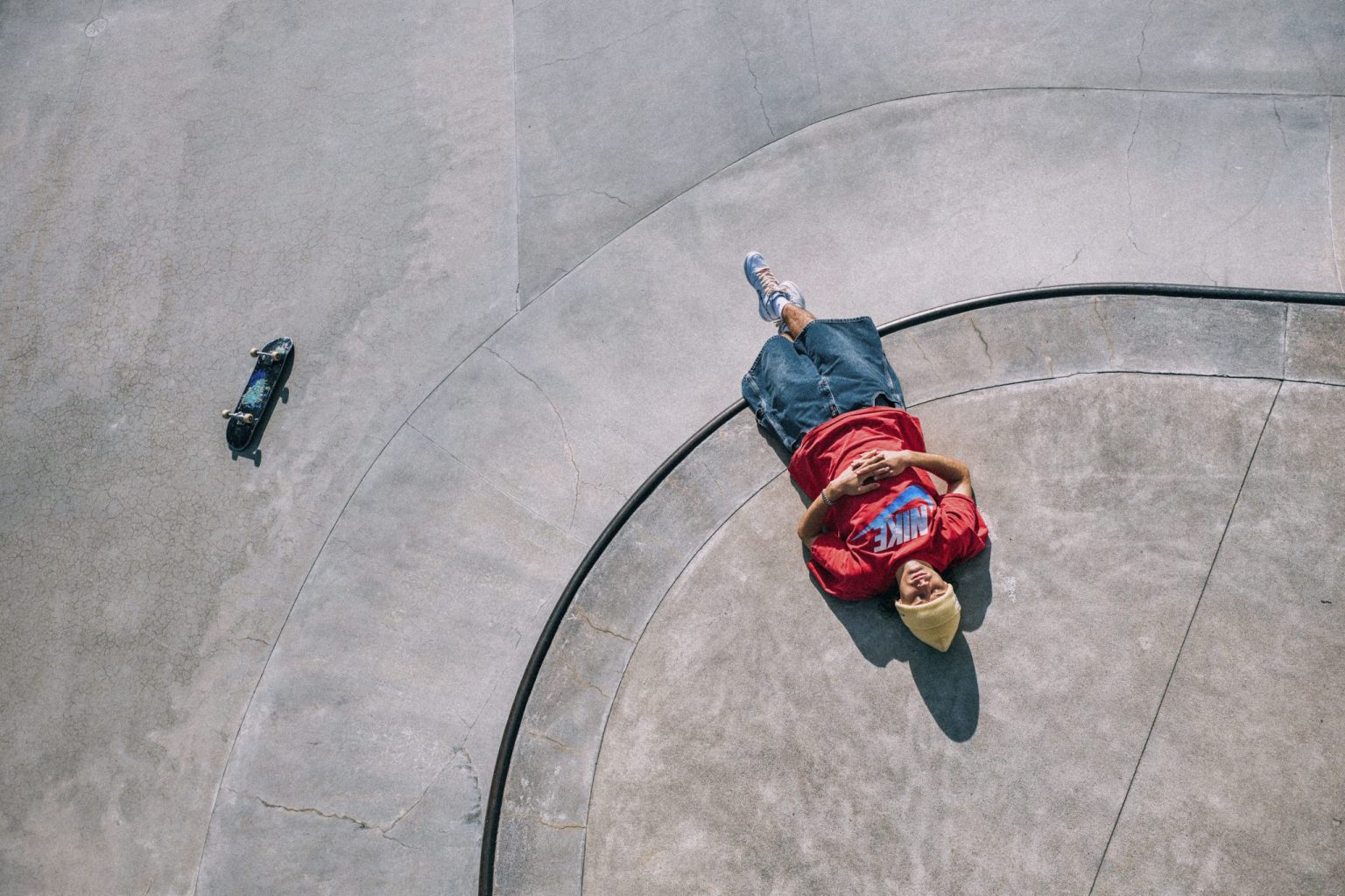a man lying on a concrete surface with a skateboard