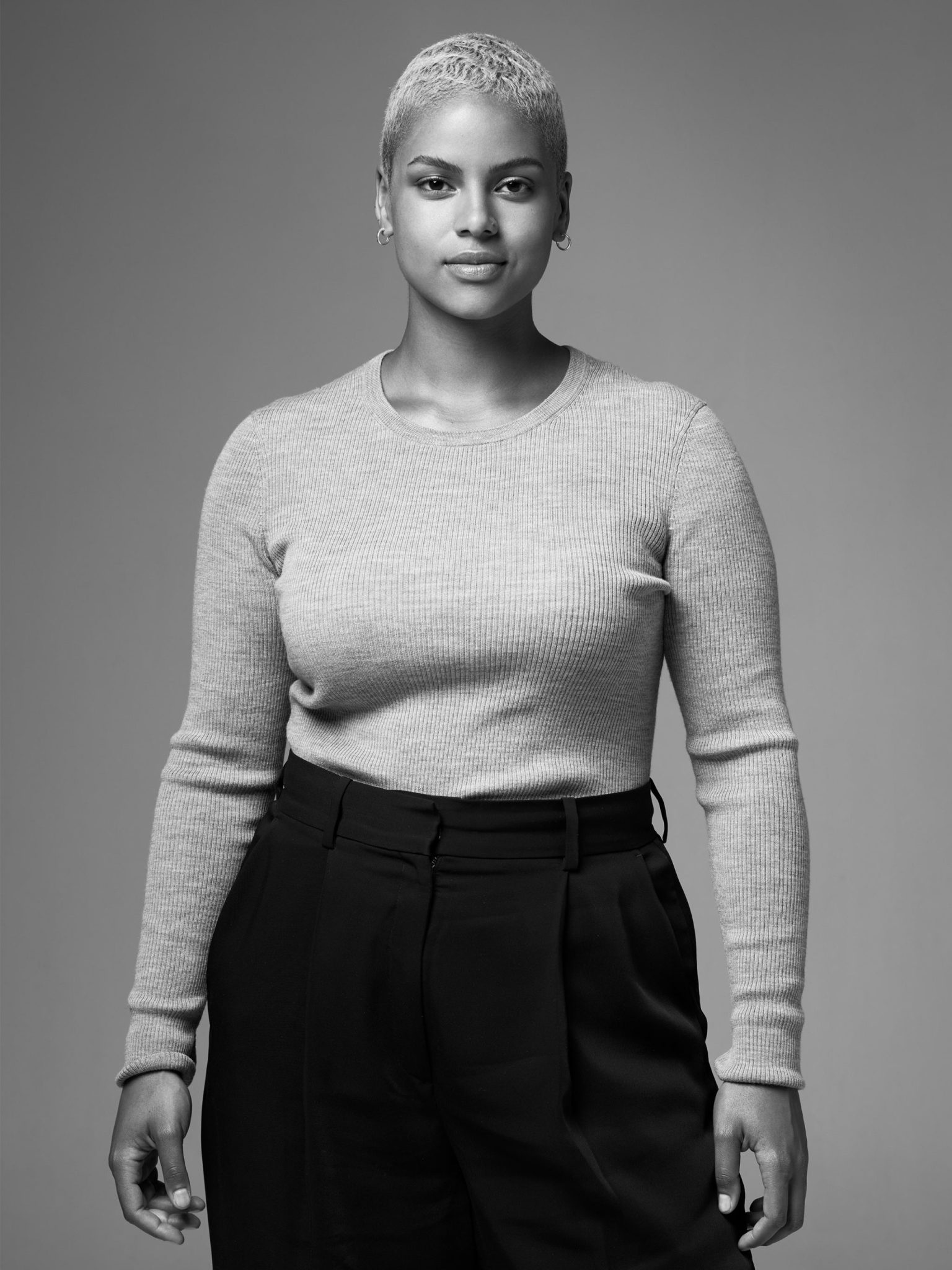 a woman with short hair wearing a sweater and black pants