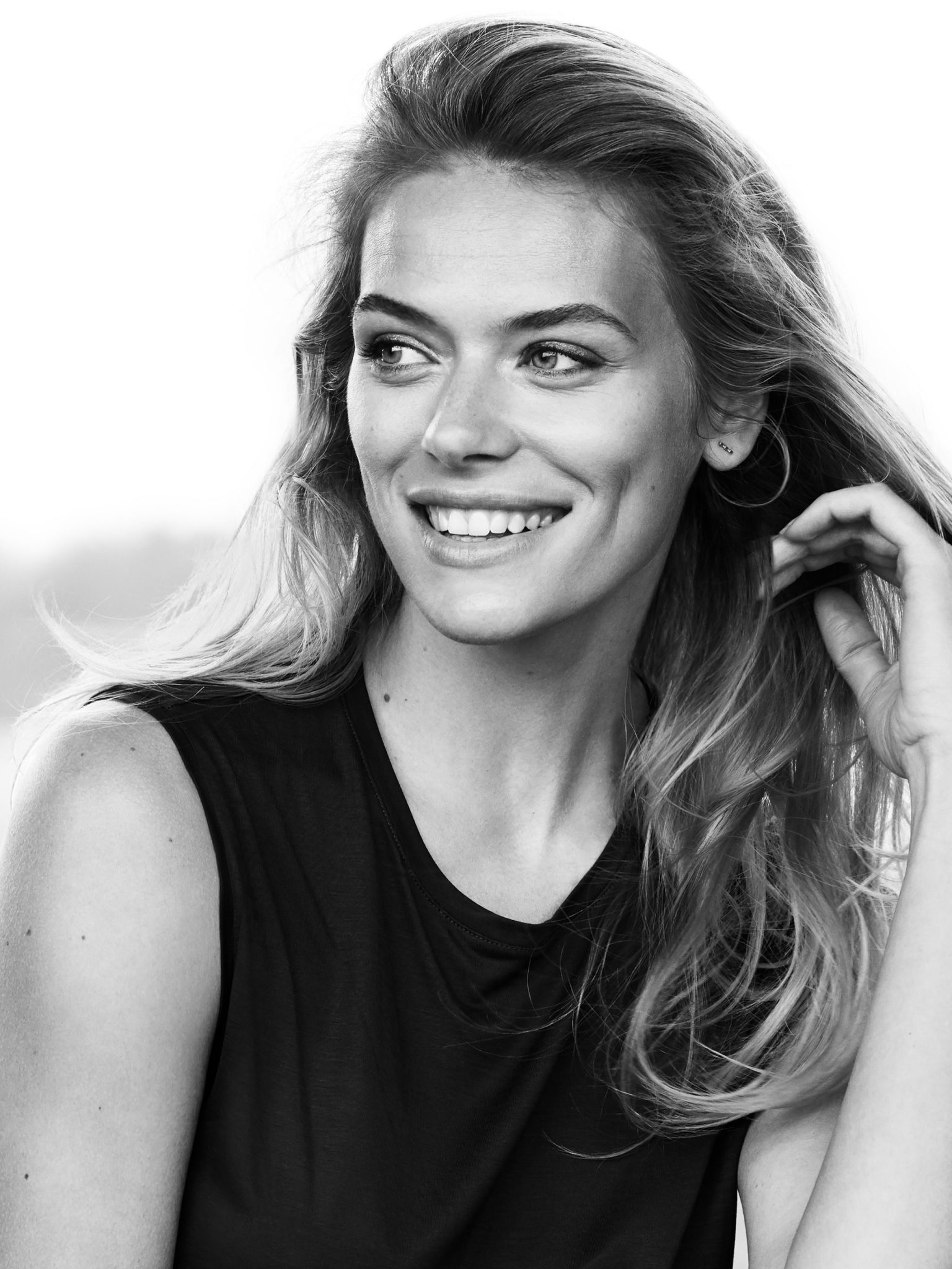 a woman smiling with her hand on her hair